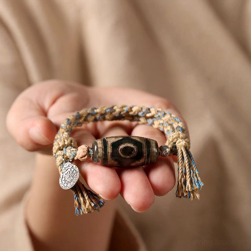 Dzi Bead spiritual bracelet held in palm with metal charm detail