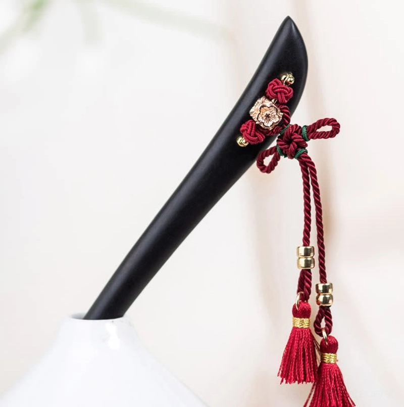Ebony hairpin side view showing smooth black wood and red knot detail