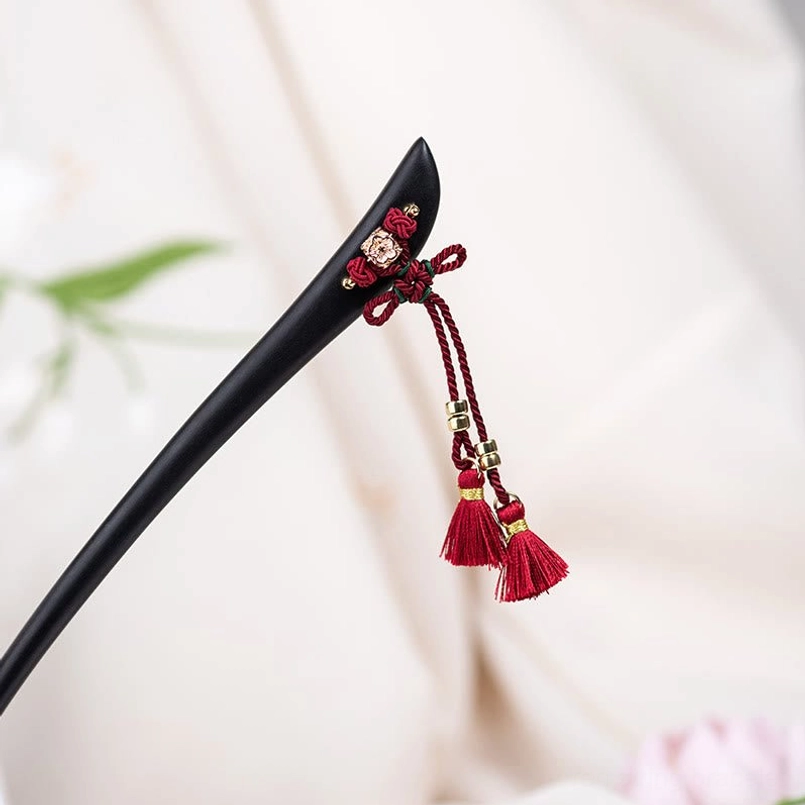 Ebony red string tassel hairpin close-up flat lay with floral ornament