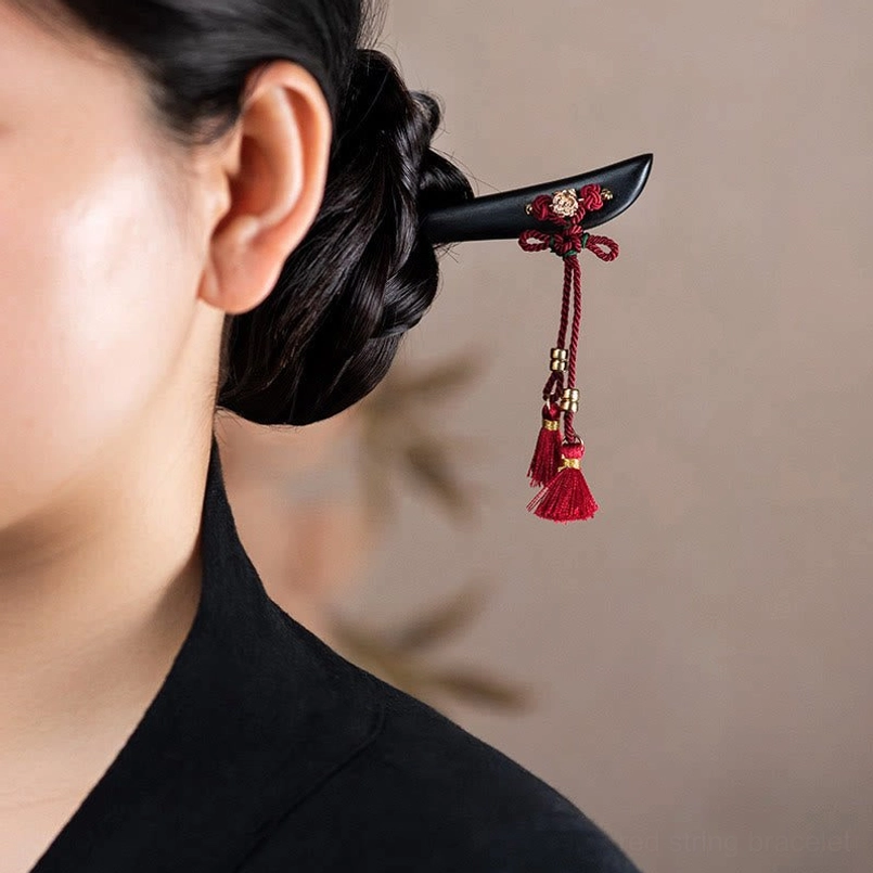 Ebony red string tassel hairpin worn in traditional hairstyle side view