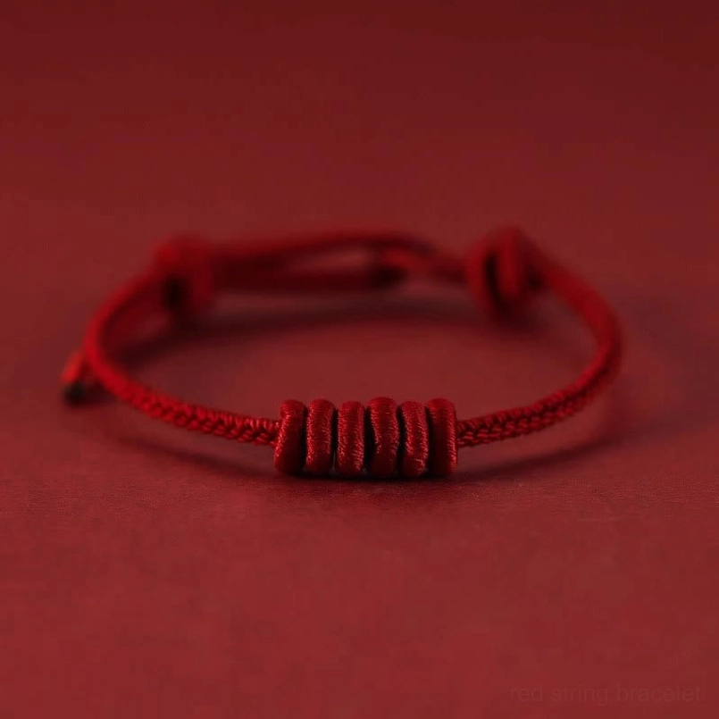 Close up view of central decorative knot on eight stranded red string bracelet