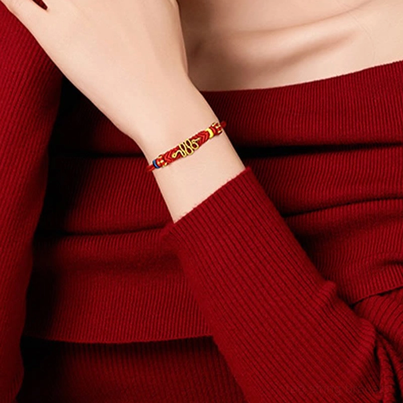 Braided red protection bracelet with gold and colored beads on single wrist, close-up side angle