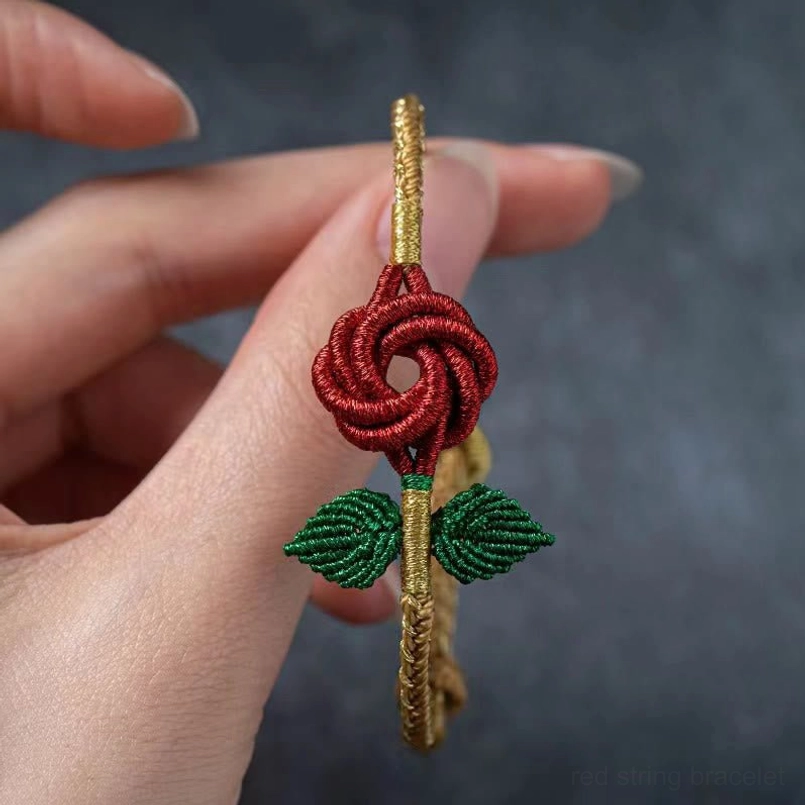 Single handmade eight thread peace knot red rose bracelet held in hand showing woven detail
