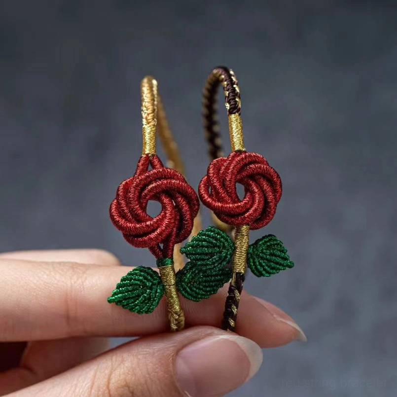 Close-up of pair of handmade red rose peace knot bracelets held in hands with braided cord detail