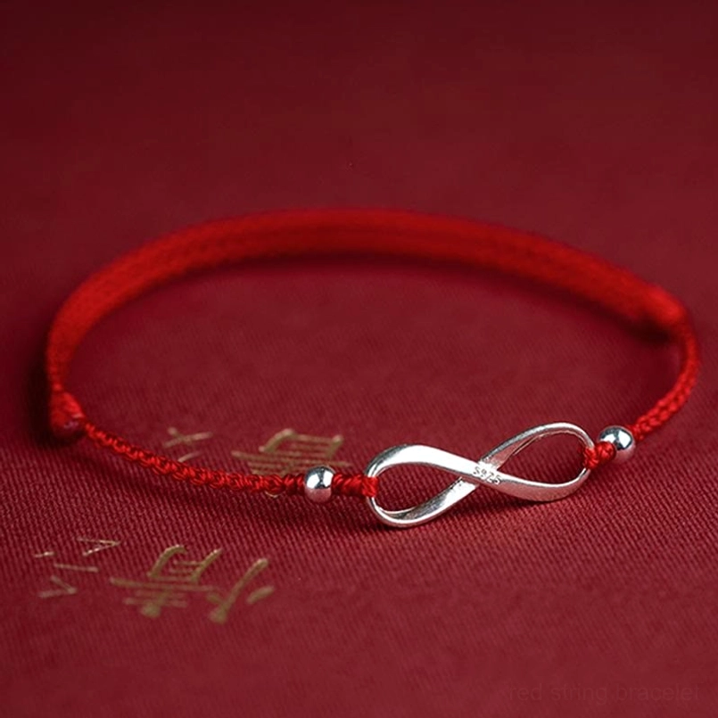 Red string bracelet with infinity knot on golden text background