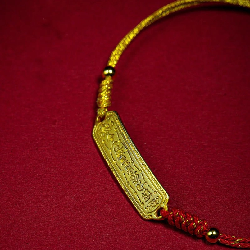 Close up of engraved 14K gold tag on red amulet bracelet