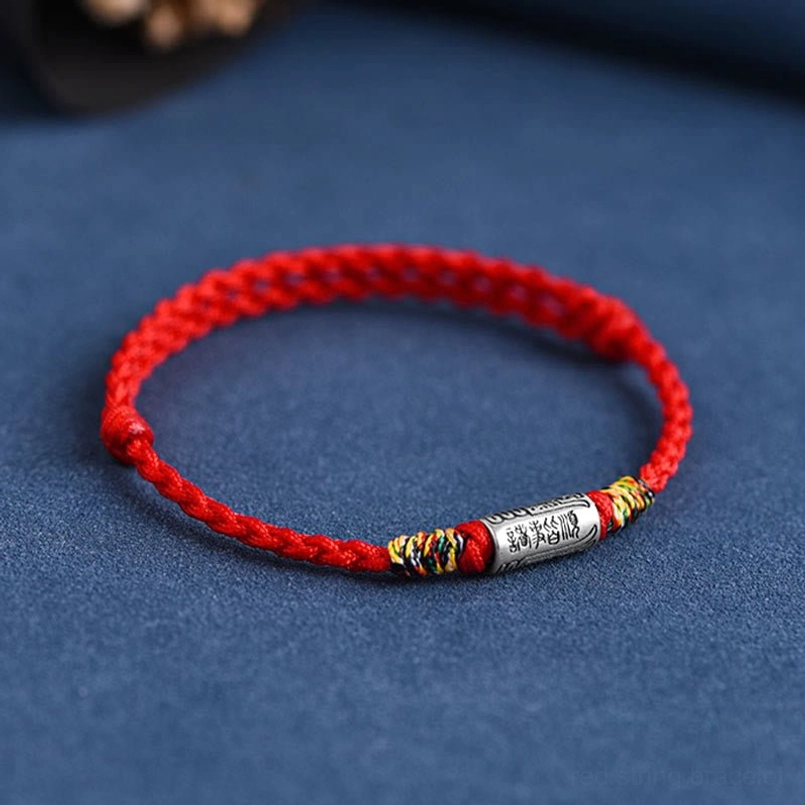 Red woven lucky bracelet with sterling silver charm and colored accent knots overhead view