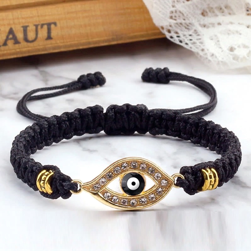Black woven rope evil eye bracelet with gold border charm and marble background