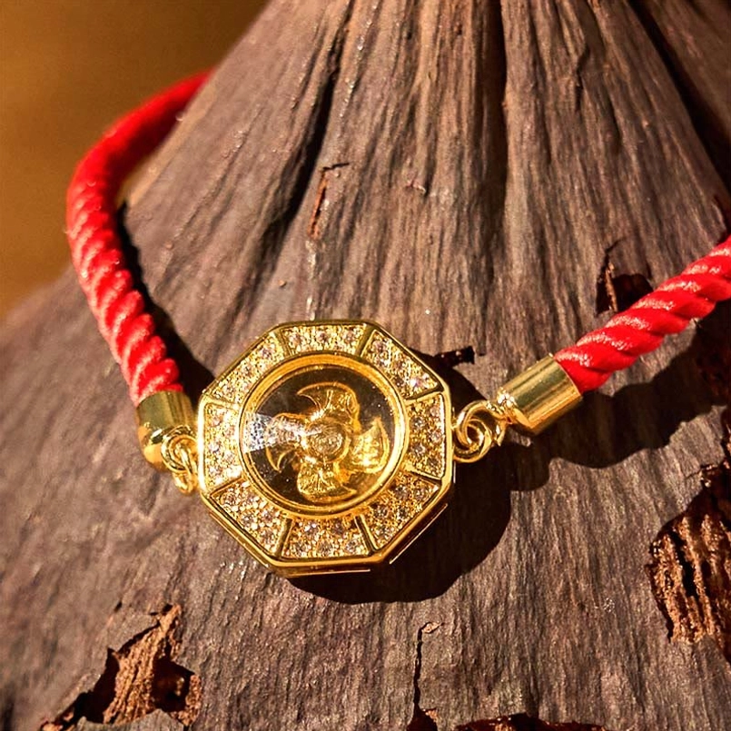 Detailed flat lay view of octagonal feng shui windmill charm with rotatable center and braided red string strap