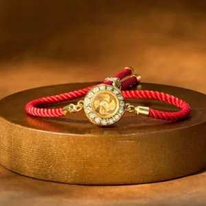 Rotating windmill red string bracelet with copper brass charm on wooden tray, top view