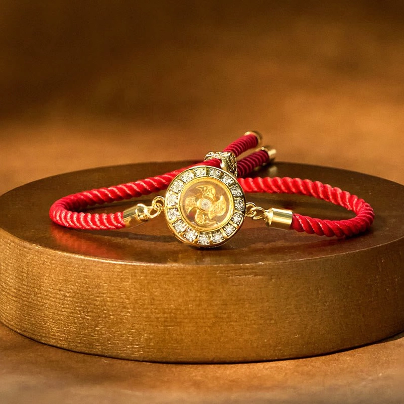Rotating windmill red string bracelet with copper brass charm on wooden tray, top view