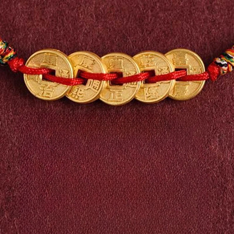 Five coin bracelet detailed view showing coin text and colorful woven end decorations