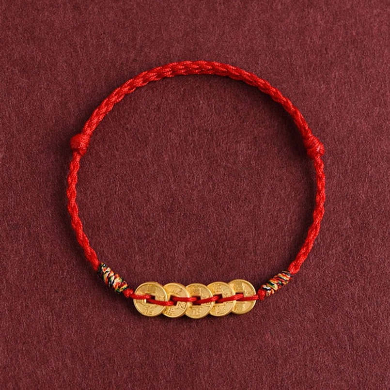 Red string bracelet five coins top-down flat lay showing golden imitation coins and colorful braided fastener