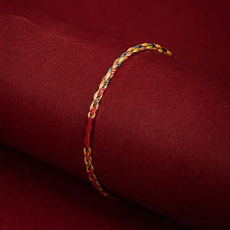 Slim multicolor woven Tibetan bracelet displayed on fabric with twisted cord texture detail