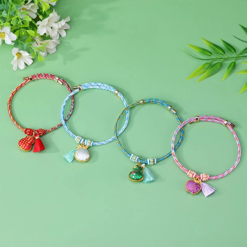 Multiple five-color braided red string bracelets with various charms displayed on light background