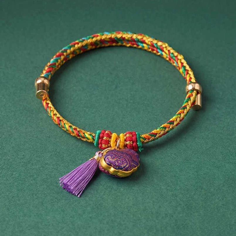 Vibrant five-color braided lucky bracelet with purple tassel pendant flat lay photography