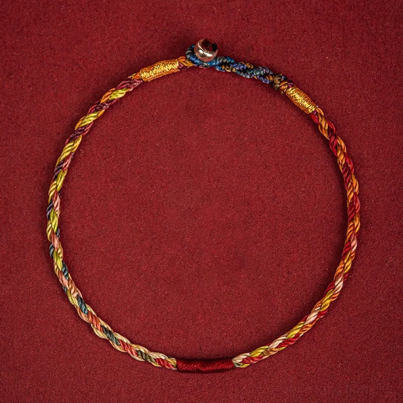 Five color Tibetan luck bracelet front overhead view with metal dark clasp and red thread end