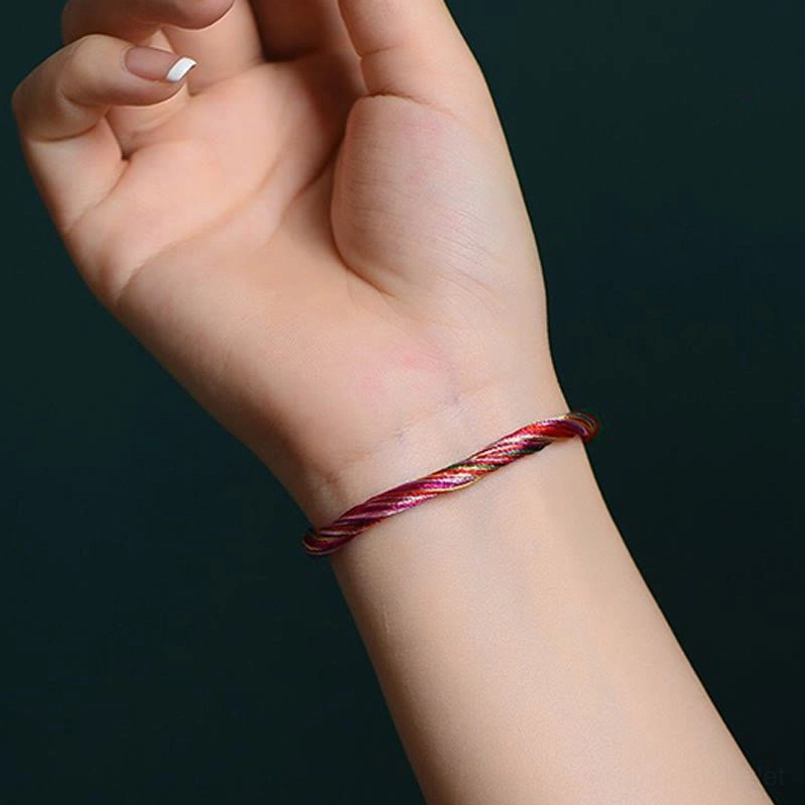 Five color red string bracelet front close up on wrist with white nail art