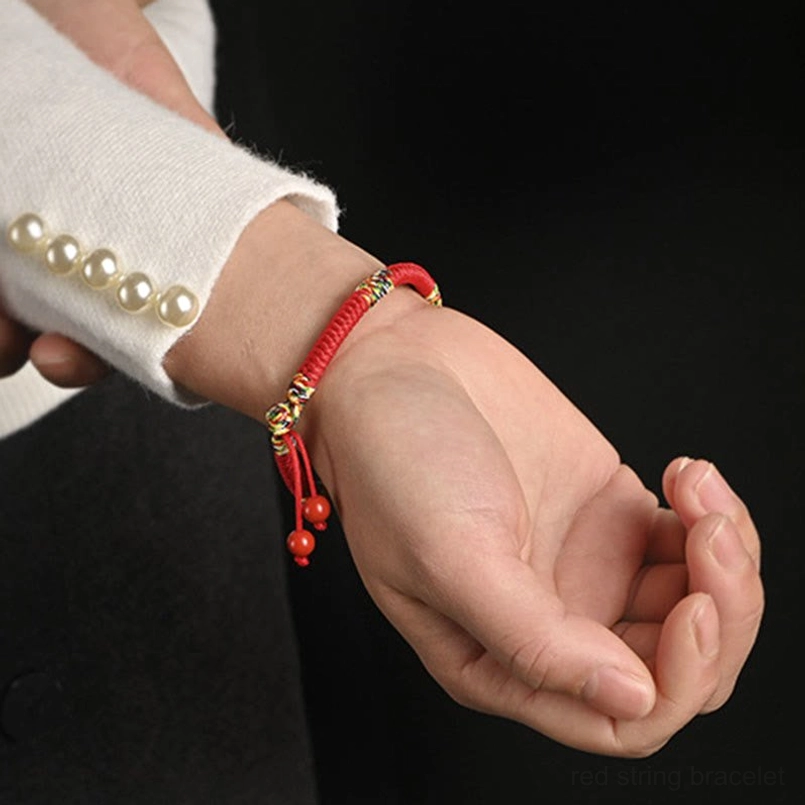 Five colors red string king kong knot bracelet worn on wrist close-up showing intricate weave and cinnabar pendants