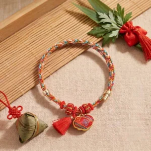 Five-color song brocade lucky bracelet with embroidered lock charm pendant, displayed on bamboo mat with festive ornaments