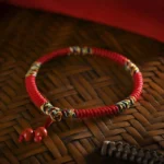 Five colors king kong knot red string bracelet with cinnabar pendants overhead flat lay view on bamboo tray