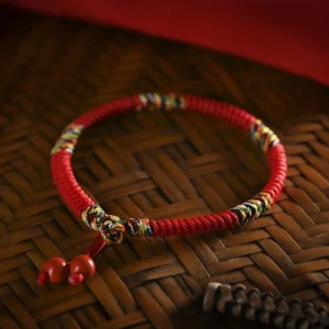 Five colors king kong knot red string bracelet with cinnabar pendants overhead flat lay view on bamboo tray