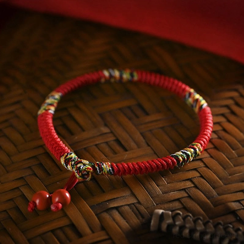 Five colors king kong knot red string bracelet with cinnabar pendants overhead flat lay view on bamboo tray