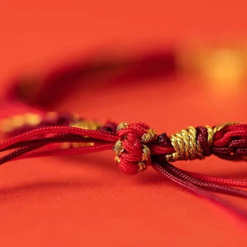 Close-up extreme detail of five directions bracelet knots showing woven red and gold rope texture and braided fastener