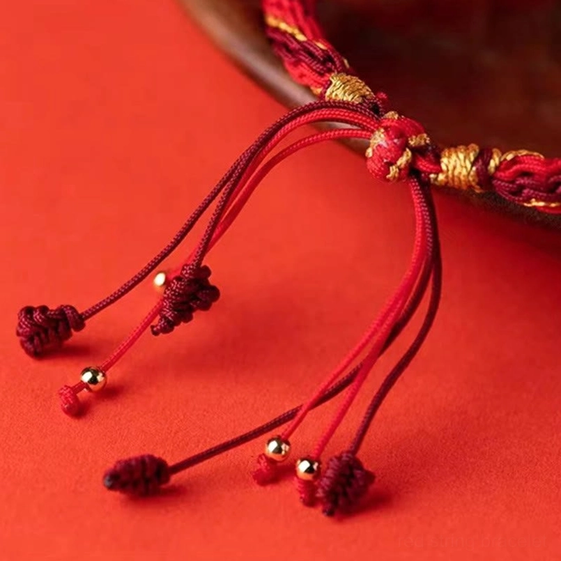 Five directions bracelet fastener detail showing tassel ends with gold beads and woven braided adjustment mechanism