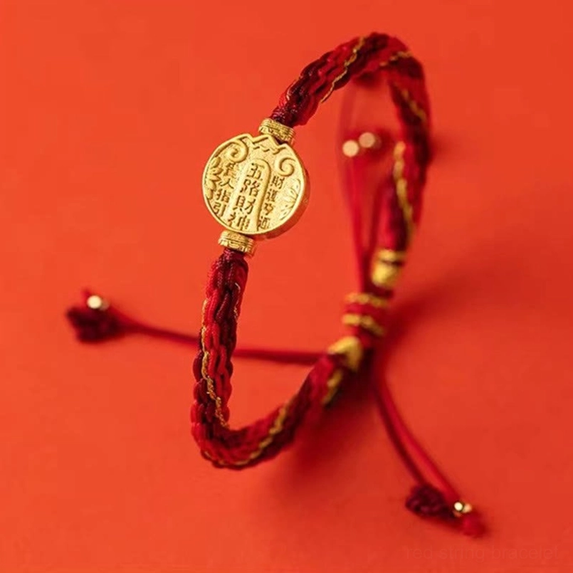 Handmade five directions wealth bracelet hanging display showing woven red and gold cord with tassel accents