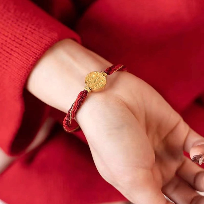 Hand wearing five directions wealth protection bracelet, front view showing adjustable red and gold woven cord