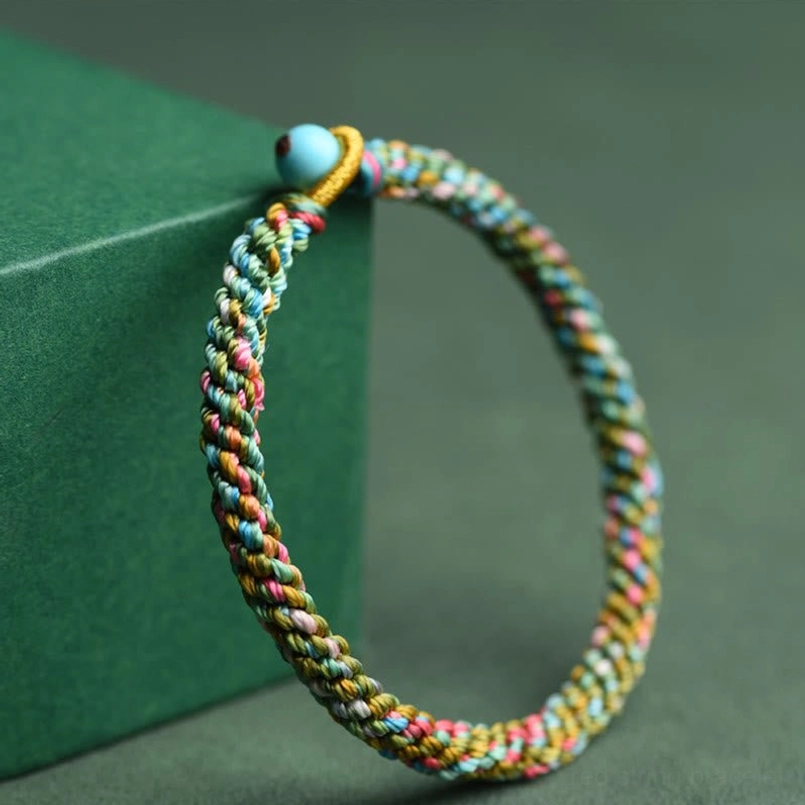 Three-quarter view of multicolor braided cord lucky bracelet with turquoise end bead in green gift box
