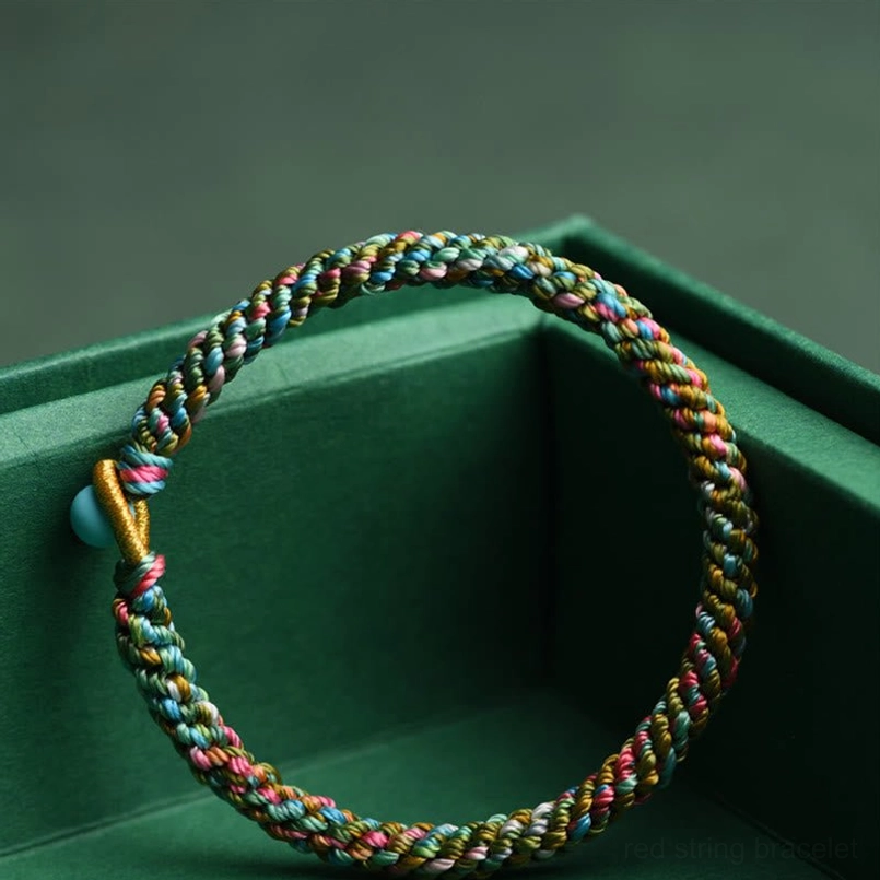 Multicolor twisted braided lucky bracelet with turquoise bead clasp detail inside green gift box packaging
