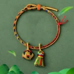 Five element colorful red string bracelet with golden ball charm flat lay dark background