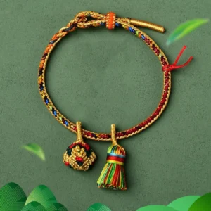 Five element colorful red string bracelet with golden ball charm flat lay dark background
