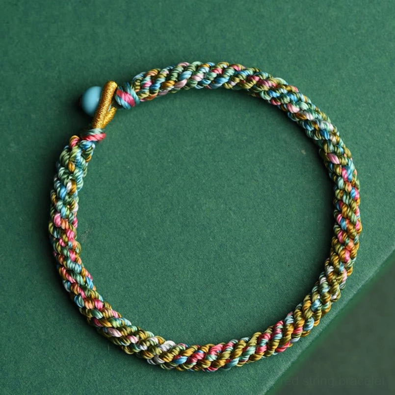 Top-down flat lay view of handwoven multicolor lucky bracelet showing intricate braided rope pattern and turquoise bead