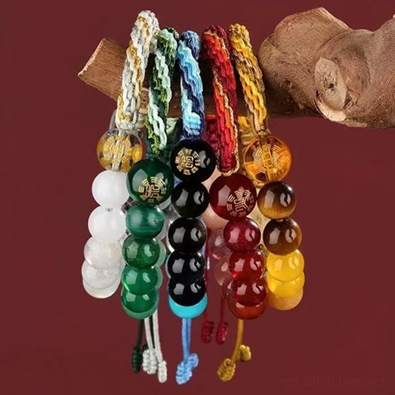 Multiple five elements feng shui crystal bracelets displayed with wooden props and wine-red backdrop