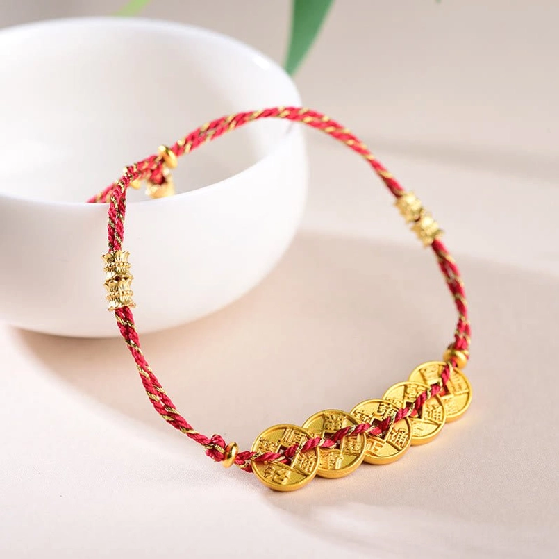 Close-up side view of woven red rope with ancient emperor coins and gold spacer beads