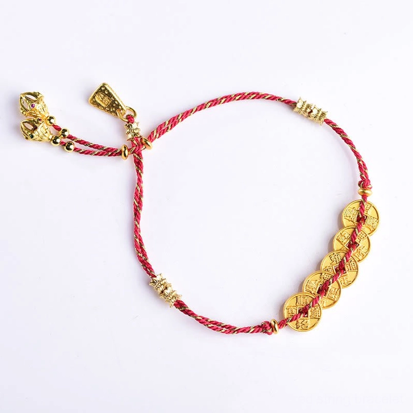 Flat lay side view of woven red string bracelet with five copper coins and tassel clasp
