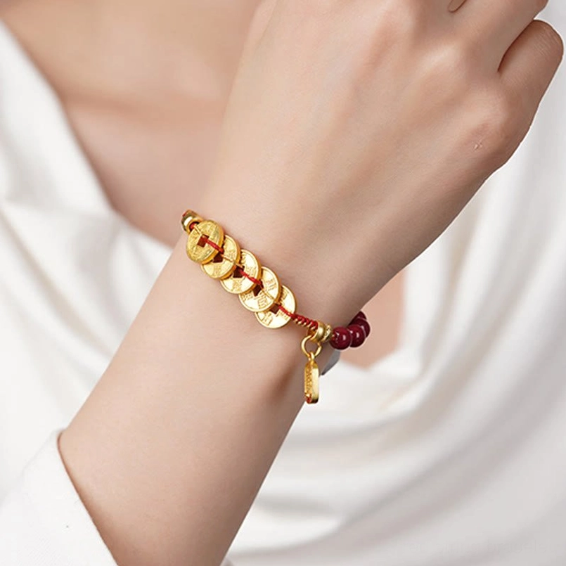 Five-emperor coins red string bracelet worn on wrist with white top