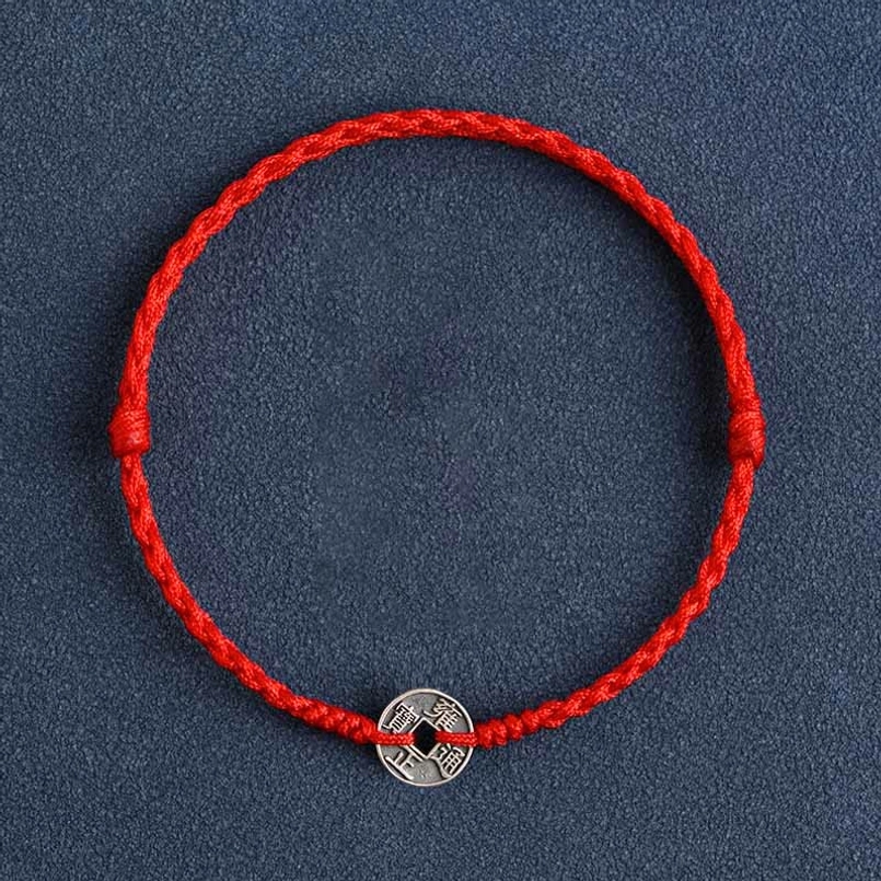 Overhead flat lay of circular braided red string bracelet with centered 925 sterling silver coin