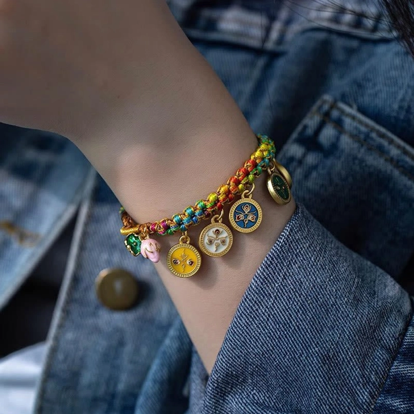 Colorful braided Tibetan Five God bracelet worn on wrist with denim jacket background