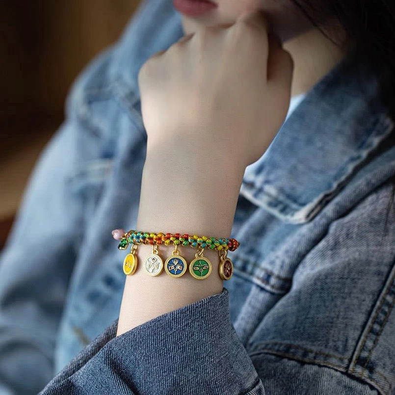 Five God of Wealth Tibetan bracelet with multicolor braids and enamel deities on denim