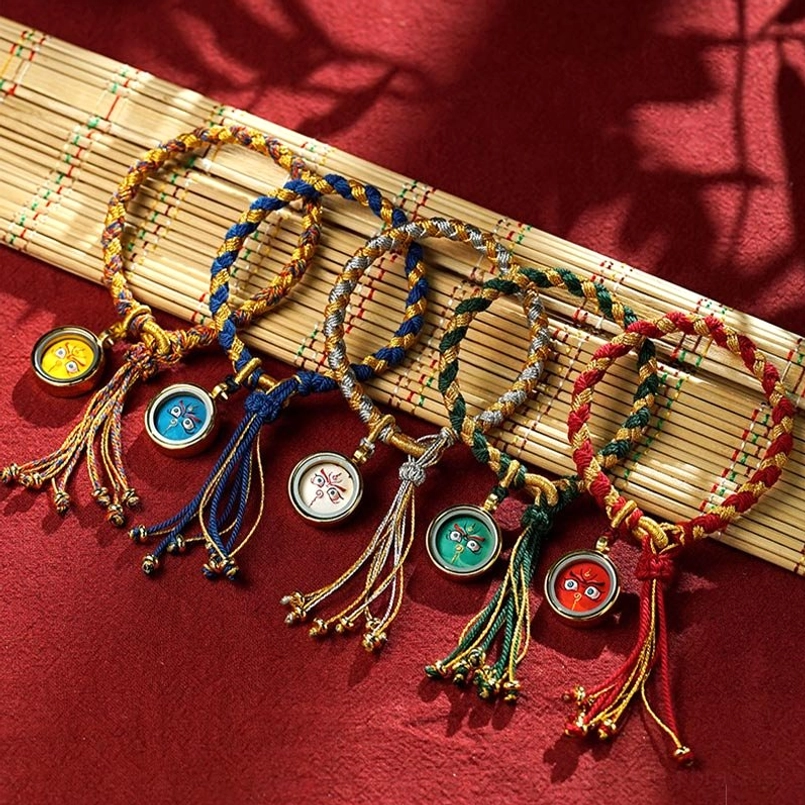 Multiple tibetan braided wealth bracelets in various colors displayed flat lay on bamboo mat