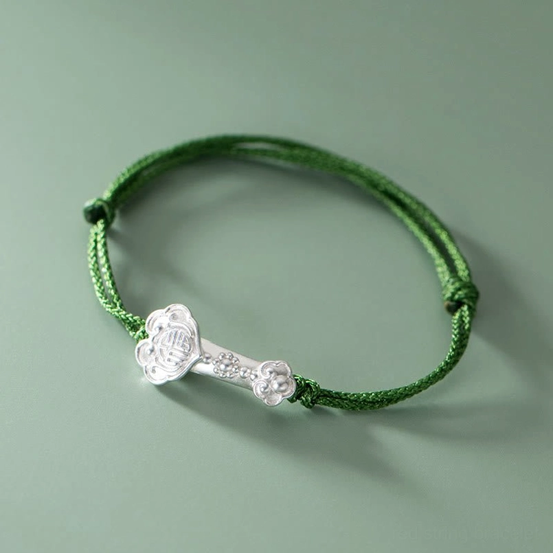 Top down flat lay view of adjustable silver ruyi charm green braided bracelet
