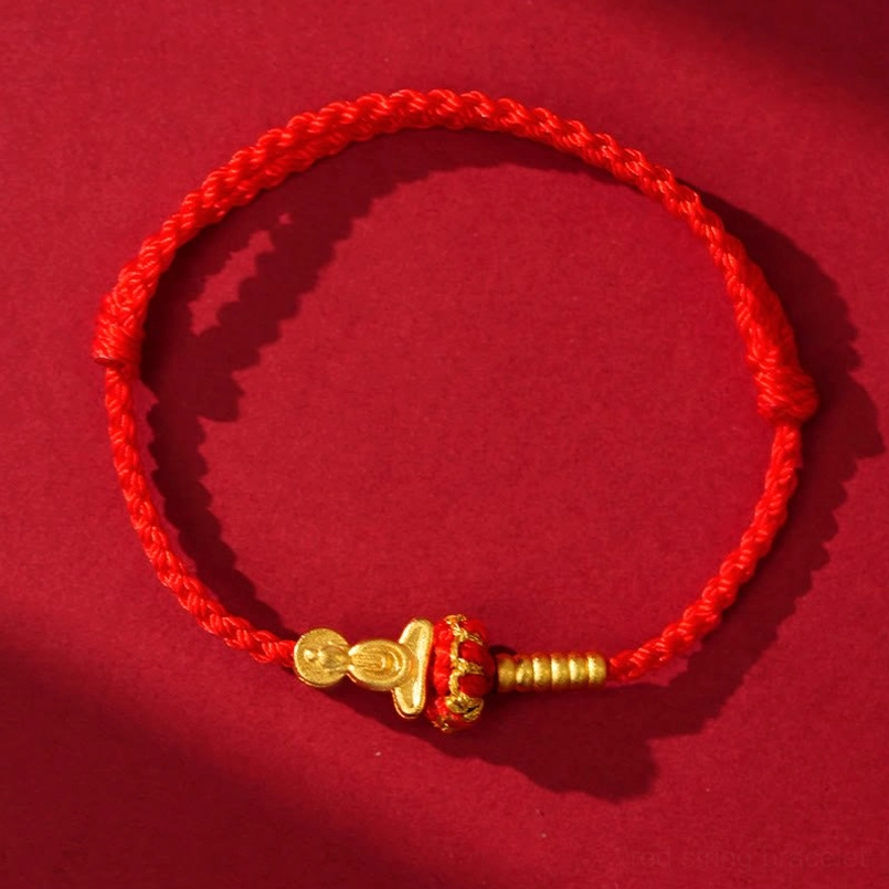 Red string protection bracelet with gold-plated metal beads and decorative accents overhead view