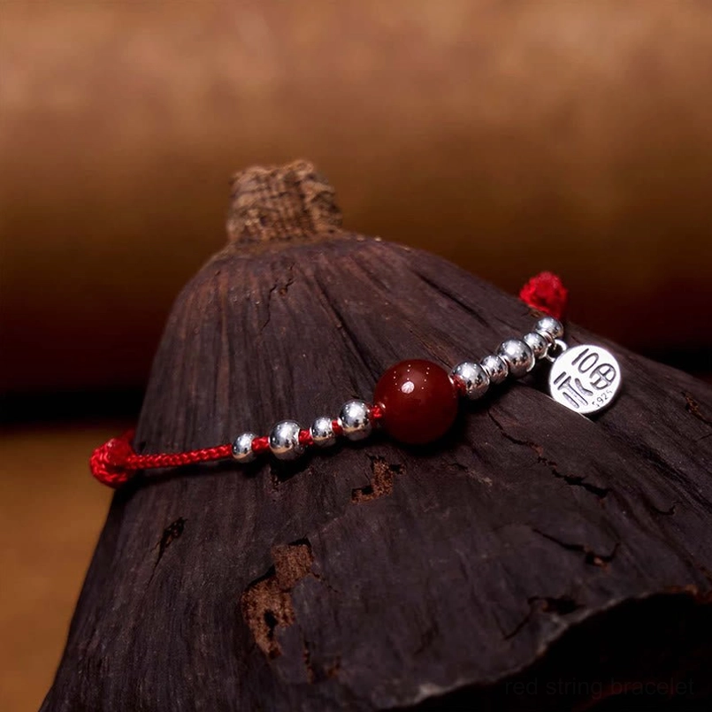 Handmade red agate and silver Fu pendant bracelet on dark wooden surface
