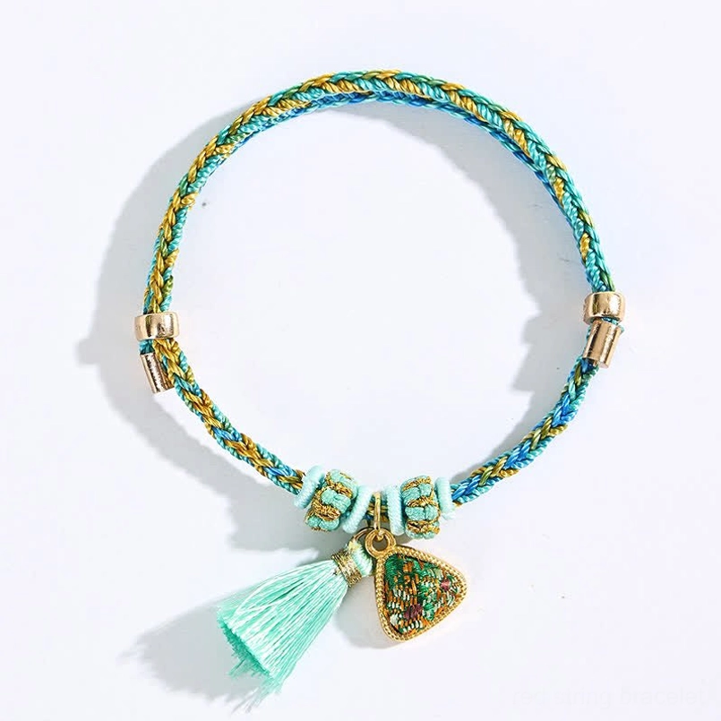 Adjustable lucky red string bracelet with Song Brocade fabric woven cord turquoise tassel and enamel charm flat lay white background