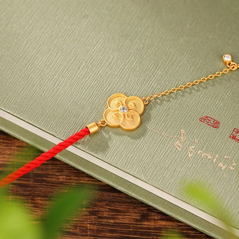 Red string bracelet with gold-plated clover charm and extender chain side view