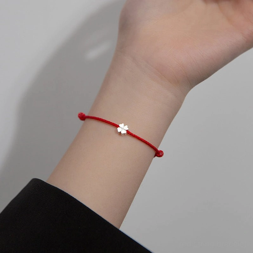 red string four leaf clover bracelet worn on wrist with formal black sleeve